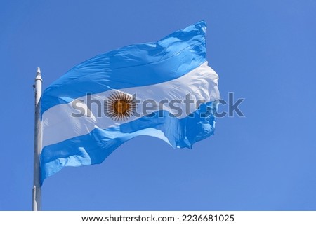 Argentinean flag on a clear blue sky background. Blue and white National symbol of Argentinean culture and patriotism.