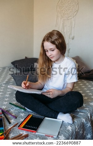  The girl after school plays at home, draws with pencils and felt-tip pens