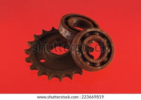 Close up photo of gear wheels and cogs on a red background.