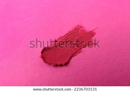 Smear of beautiful lipstick on pink background, top view