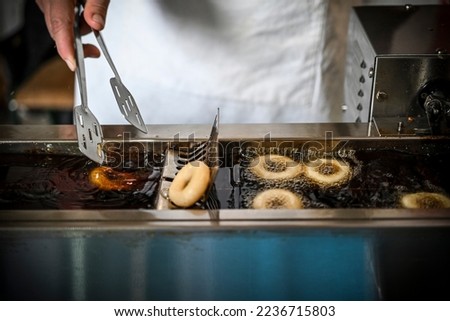 A woman's hand in the process of frying small donuts in the deep oil  Royalty-Free Stock Photo #2236715803