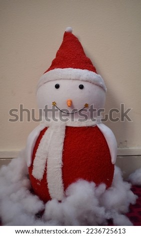 Snowman with a red cap and red clothes placed in the snow
