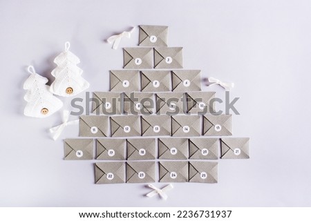 Envelopes for the advent calendar in the form of a Christmas tree and knitted fir trees on a gray background