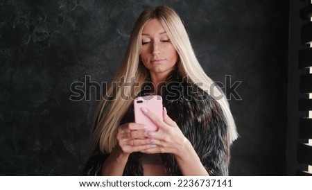 Fashionable beautiful blonde woman in a fur coat, a blogger, makes a selfie for social networks.