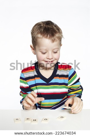 Schoolboy learning to spell with wooden letters, studio