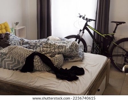 Mess in the bedroom, uncleaned room, everyday laziness in life with a bicycle standing in the back Royalty-Free Stock Photo #2236740615