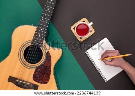 Flat lay, acoustic guitar and notebook on color background.