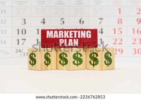 Business planning concept. Against the background of the calendar there are cubes with the image of the dollar and a red plate with the inscription - Marketing plan