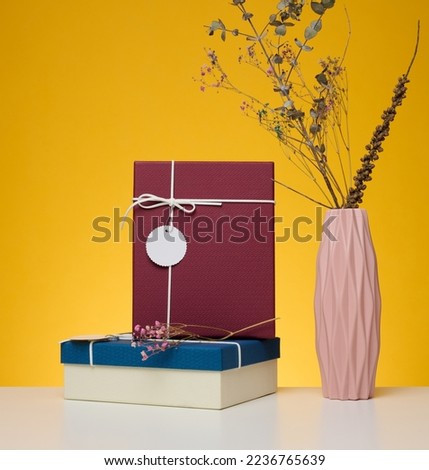 A stack of gift boxes wrapped in colorful paper on a yellow background. Happy Holidays