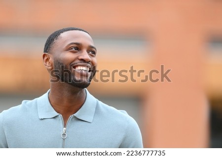 Happy black man looking above walking in the street Royalty-Free Stock Photo #2236777735