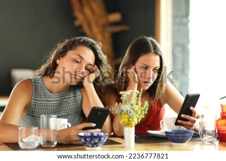 Bored friends checking smart phones in a restaurant Royalty-Free Stock Photo #2236777821