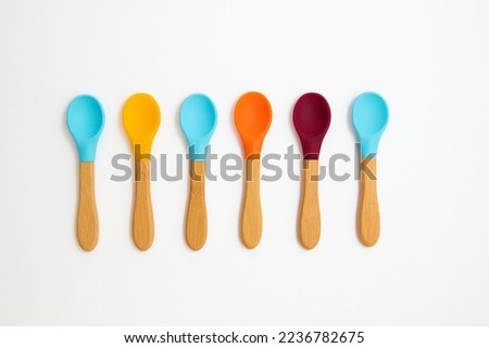 Six silicone spoons with bamboo handles of different colors on a white background. Cutlery is safe for babies Royalty-Free Stock Photo #2236782675