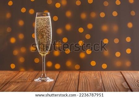 Glasses with champagne on a wooden background against a bokeh background of lights close-up