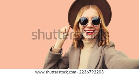 Fashionable portrait of stylish happy smiling young woman stretching hand for taking selfie with phone