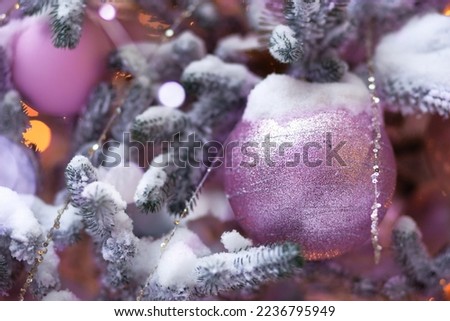 viva magenta ball with sparkles on Christmas tree with snow flakes outdoor. Christmas decoration. pantone color of the new year 2023
