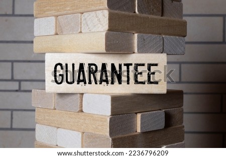 Text GUARANTEE on wood cube block, stock investment concept. The text GUARANTEE is written on the cubes in black letters, the cubes are located on a blue glass surface