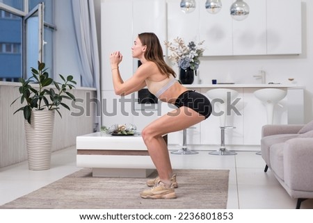 Young woman practicing squats. Woman exercising at home Royalty-Free Stock Photo #2236801853