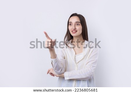 Happy young caucasian female in a shirt pointing fingers away