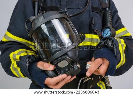 Full protective breathing air mask in hand of unrecognized african-american firefighter, rescue and fire fighter equipment 