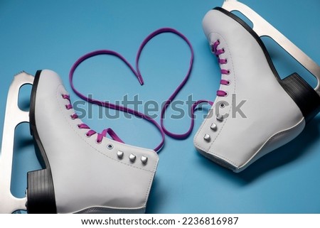 Heart shape created from shoelaces. White female figure skates on blue background.