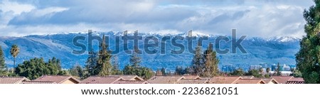 Aerial view of stucco roof of residential buildings. Blurred panoramic view of snow covered San Francisco Bay Area peaks of Diablo mountain range.