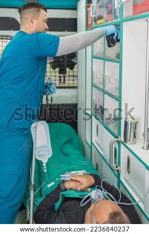 Vertical photo of a doctor working in an ambulance next to a patient on a stretcher