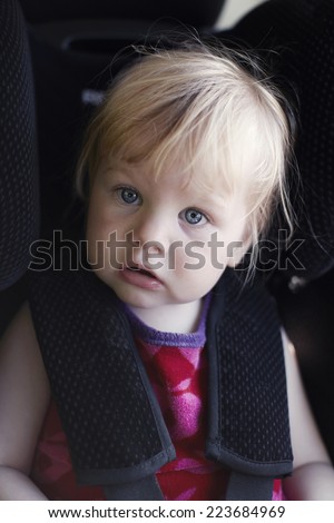Portrait of little girl in child's car seat, close up
