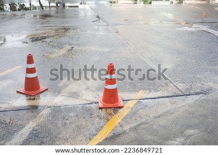 The cone is placed on the concrete floor of the parking lot.