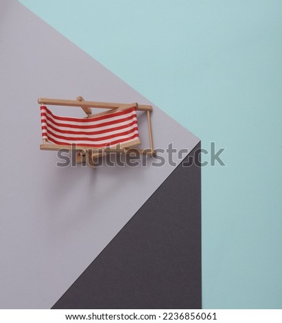 Deck chair on a paper cube. Optical illusion. Geometric composition. Minimalistic creative layout