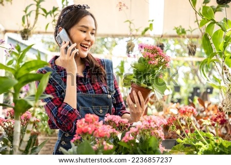 Asian woman using a smartphone photographing flowers in the flower garden. Order in plants shop. Woman in nursery plant working with flowers