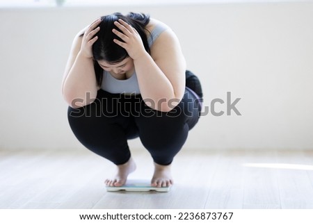 A woman holding her head on a weight scale Royalty-Free Stock Photo #2236873767