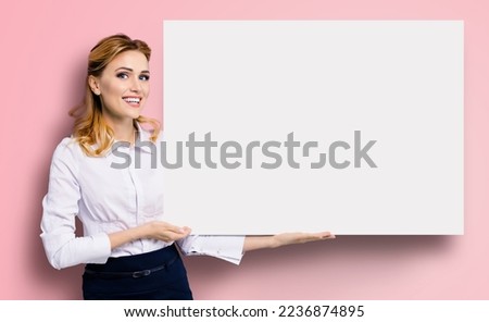 Happy excited smiling business woman in white confident clothing showing blank banner signboard. Success and advertising concept. Copy space empty place for some text. Rose pink background.