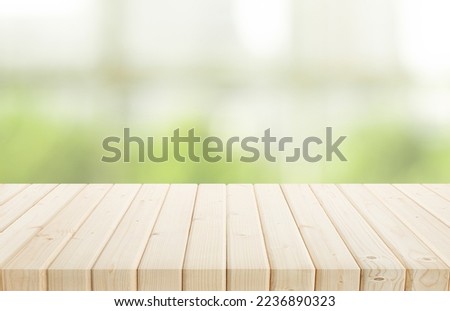 Selective focus.Wood table top on blur of window with garden flower background in morning.For montage product display or design key visual layout