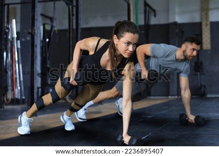 Strong man and woman holding dumbbells in plank position at the gym Royalty-Free Stock Photo #2236895407