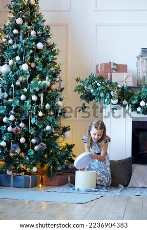 a girl dressed in a dress sitting in a room with Christmas decoration