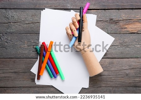Paper sheets with felt-tip pens and holder on dark wooden background
