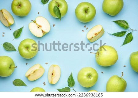 Frame made of whole and cut green apples on color background