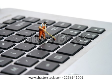 Miniature people toy figure photography. Sweeper workers cleaning notebook laptop keyboard using broom, brush. Isolated on white background. Image photo
