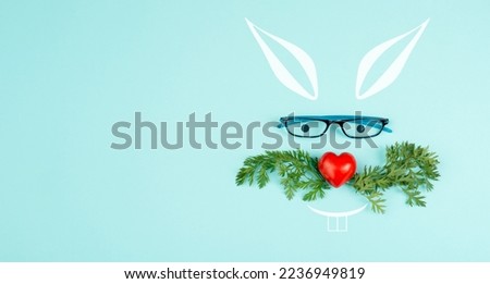 Easter rabbit face with a heart shaped nose, whiskers from carrot leaves and eyeglasse, holiday greeting card, spring season 