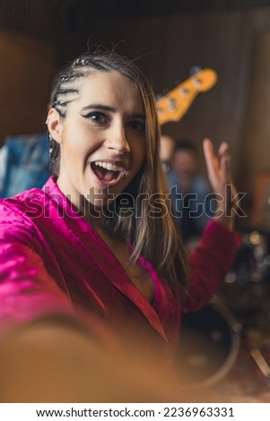 Excited stylish female vocalist takes a photo of herself during band practice. Musicians and recording studio concept. High quality photo