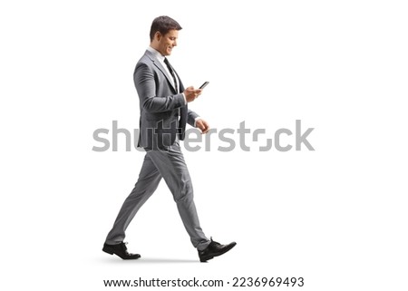Full length profile shot of a professional man using a smartphone and walking isolated on white background