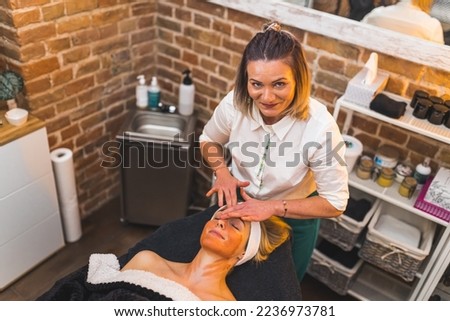Professional beautician doing a facial skin massage to a woman in a spa salon. High quality photo