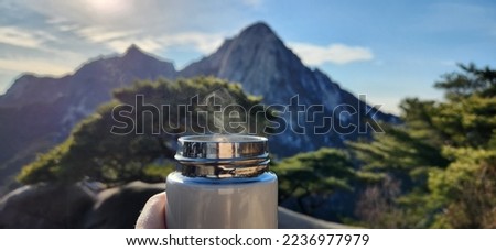 Bukhansan , Yeongbong Peak, South Korea - Hiking in the mountains - Vacation in the mountains - Steam comes from an open thermos in winter in the mountains - Thermos on the background of mountains Royalty-Free Stock Photo #2236977979
