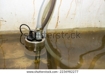 A water pump that is pumping water from flooded homes caused by storms. Royalty-Free Stock Photo #2236982277