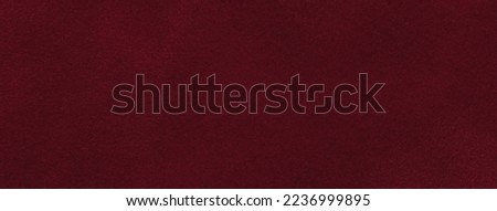 Background of dark red suede fabric closeup. Velvet matt texture of wine nubuck textile.