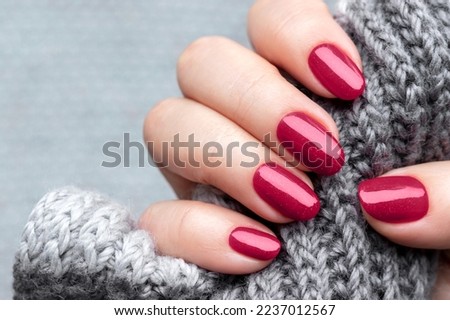 Female hand with knitted scarf and beautiful manicure - viva magenta, burgundy glittered nails Royalty-Free Stock Photo #2237012567