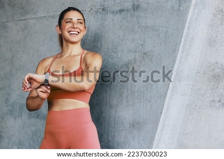 Fitness woman monitoring her heart rate with a smartwatch. Sports woman tracking her progress after a run. Happy woman doing a cardio workout outdoors. Royalty-Free Stock Photo #2237030023