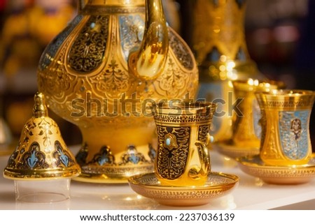 Golden tea set with traditional Turkish glass and teapot on store window display. Luxury shopping concept