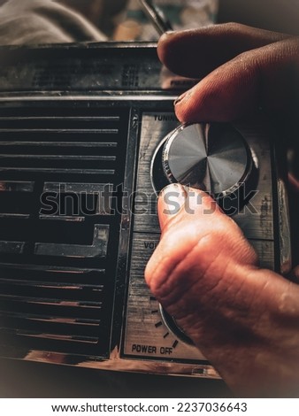 close up of a man's hand holding and listening to the radio