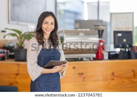 Portrait young Asian woman barista feeling happy smiling at urban cafe. Small business owner Asian girl in apron at small business entrance. Royalty-Free Stock Photo #2237043781